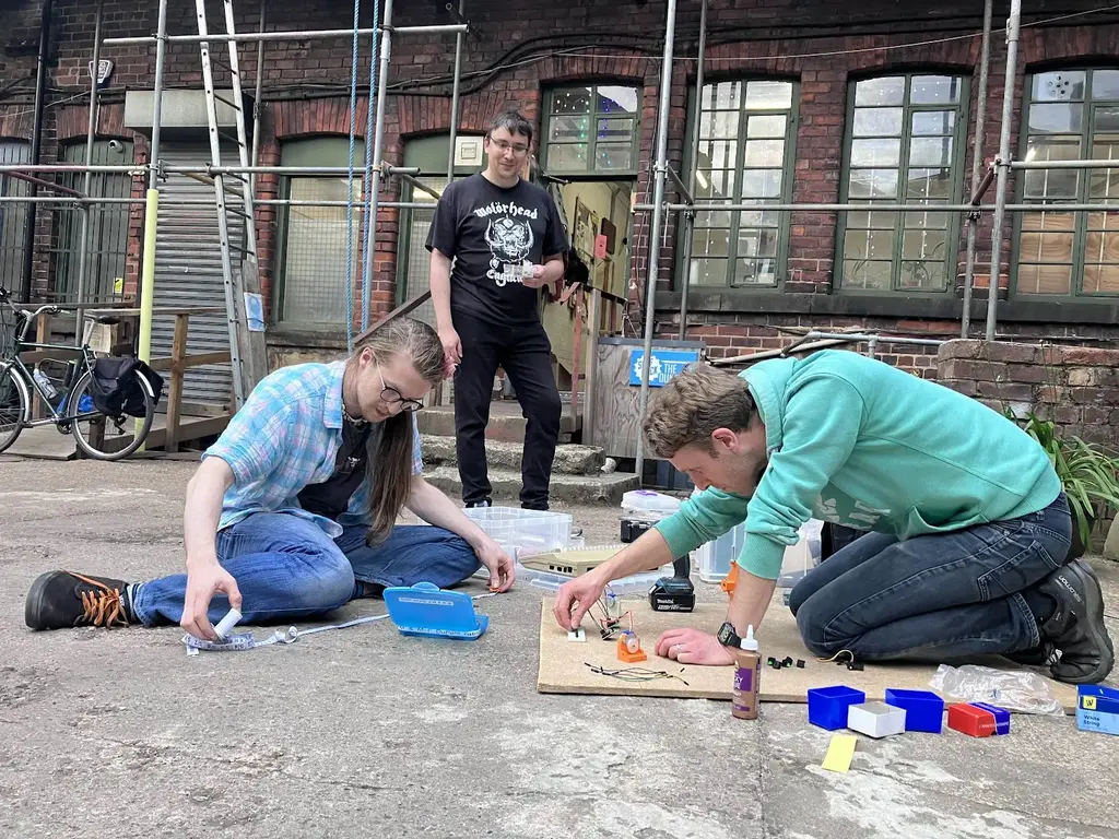 pictture of three people setting up electronics on the floor outside