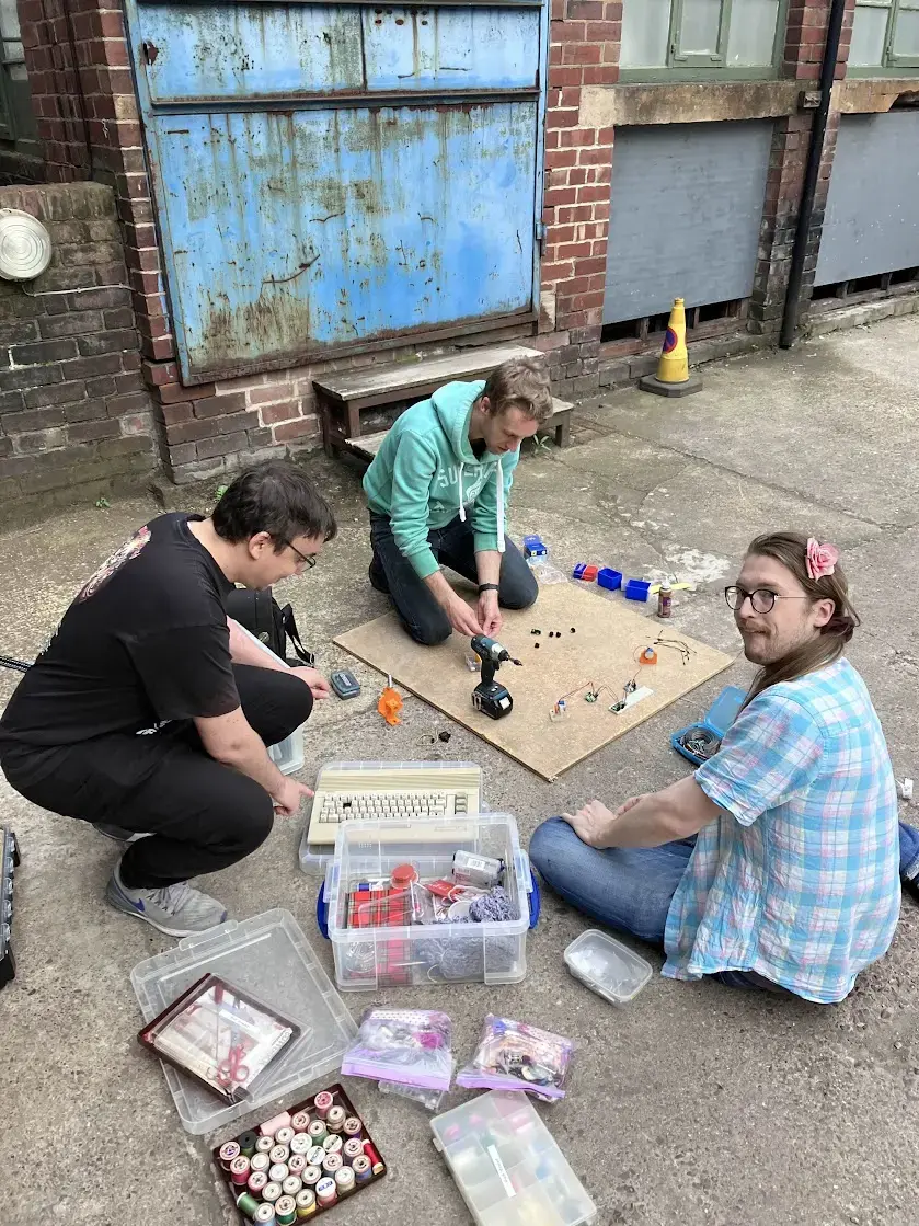 picture of three people setting up electronics on the floor outside