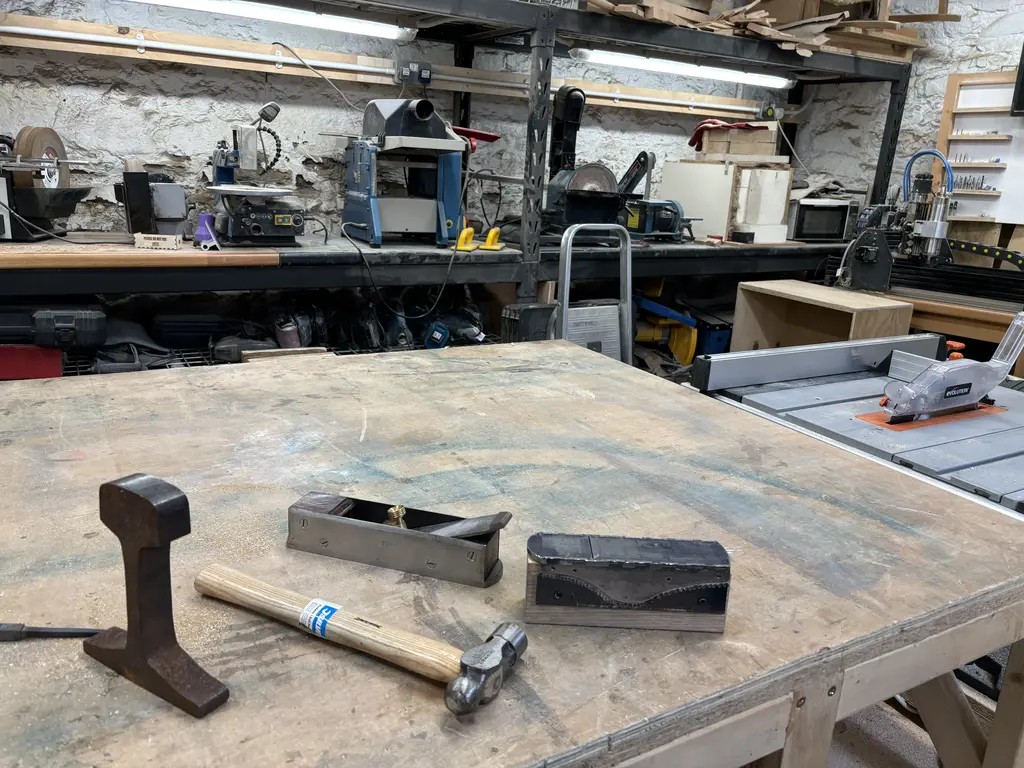 picture of partly made wood plane, in bits, on workbench